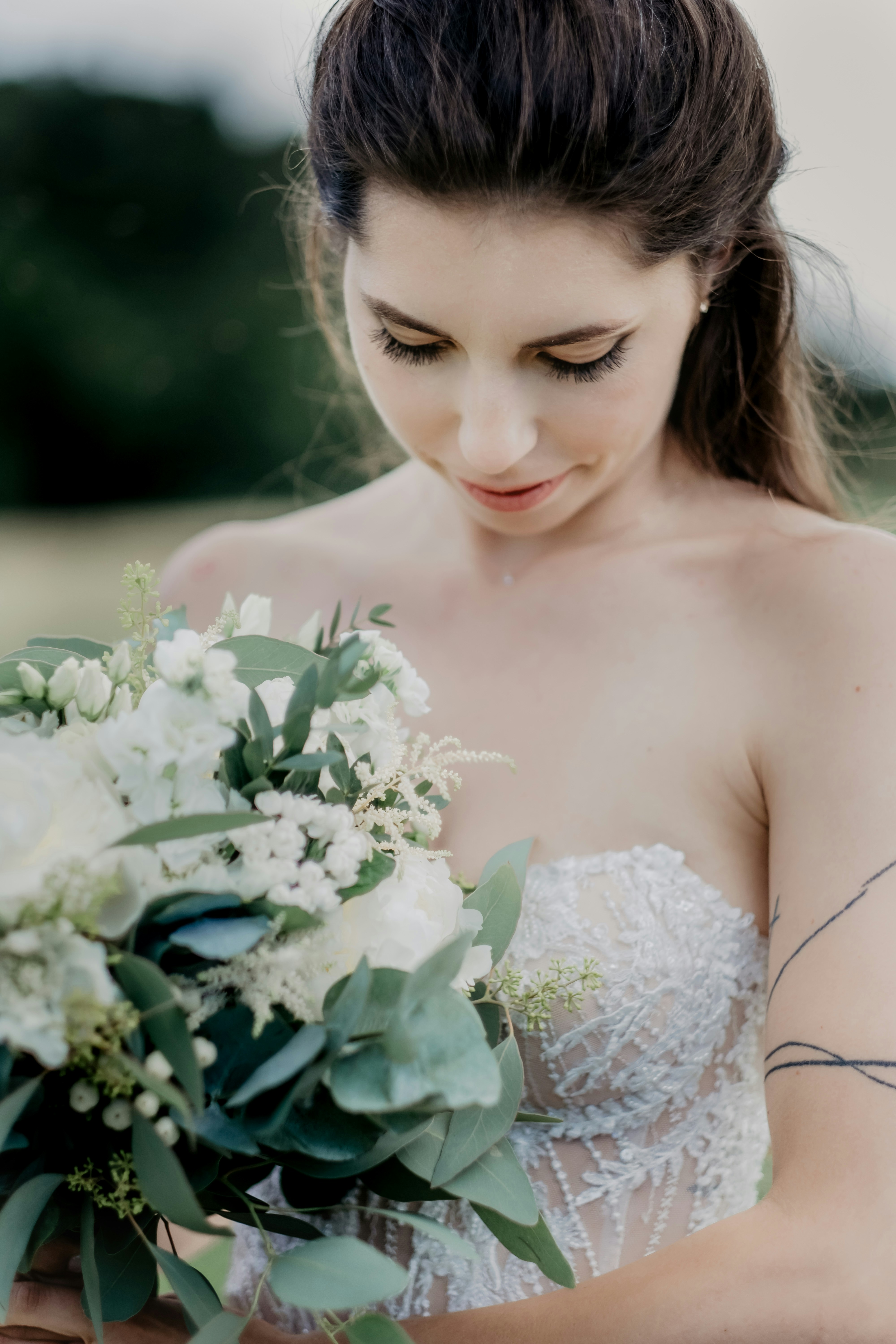 白い花の花束を持つ白い花柄のドレスを着た女性