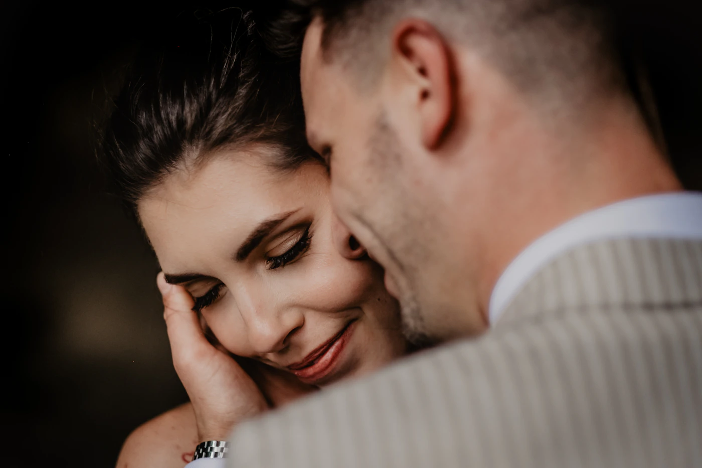 Groom in a white suit kissing his bride on the cheek