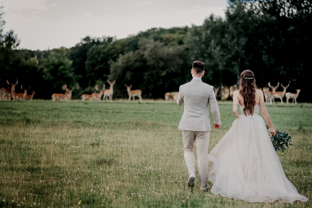 woman in white wedding gown standing on green grass field during daytime