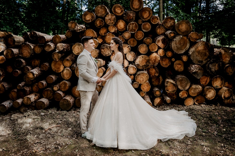 bride and groom standing beside brown wood logs