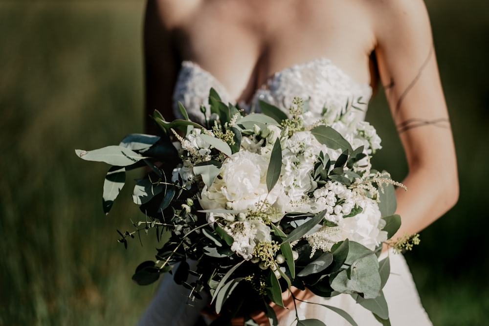 woman in white floral wedding dress holding white flower bouquet