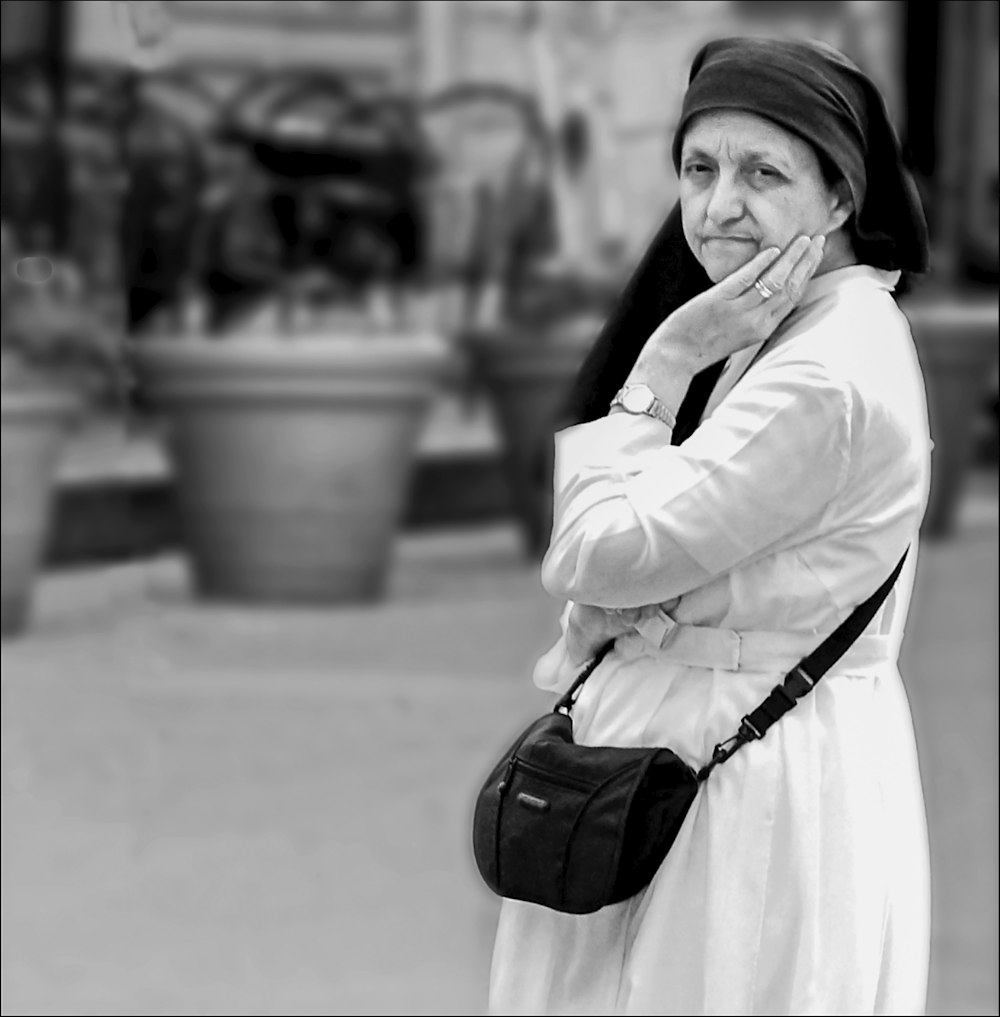 Photo en niveaux de gris d’une femme en manteau blanc et jupe noire