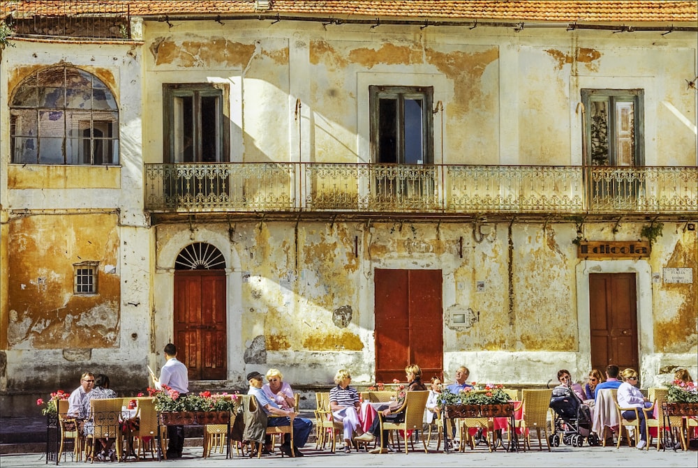 people sitting on chairs near brown concrete building during daytime