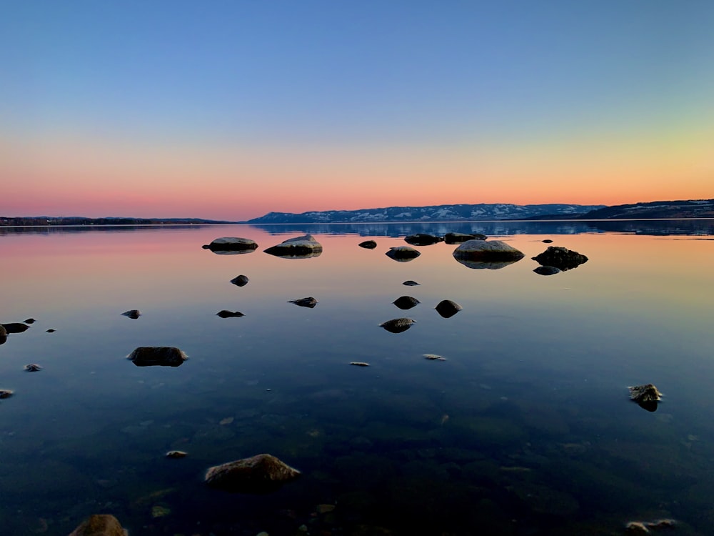 rocks on body of water during sunset