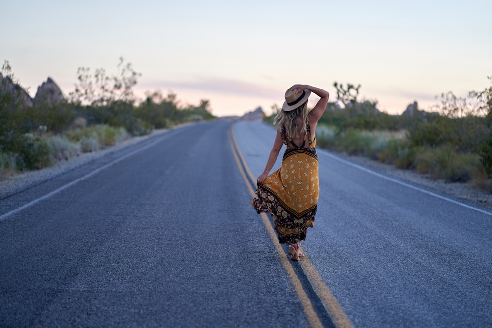 woman in black and brown dress wearing brown hat standing on road during daytime