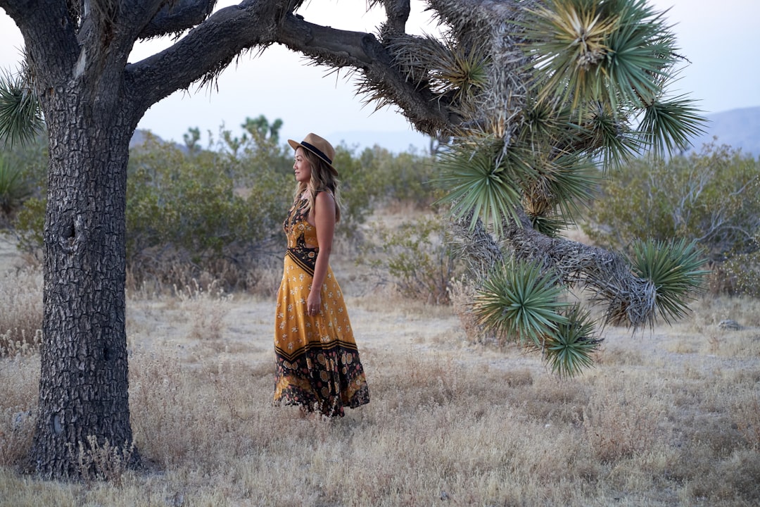 woman in brown and black dress standing near green palm tree during daytime