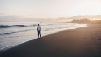 Person walking alone on beach at sunset, reflecting on trauma and healing
