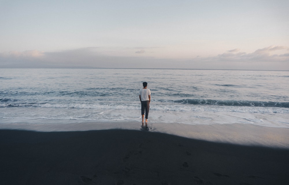 man in black shirt and black shorts standing on beach during daytime