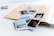 A collection of instant photographs scattered over an open scrapbook with a chevron pattern on the cover. The photos depict various scenes, including landscapes and people, and are casually arranged over a white surface.
