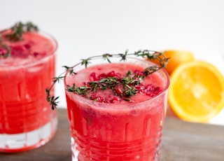 clear drinking glass with red liquid and sliced lemon