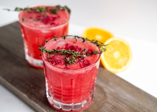 clear drinking glass with red liquid and sliced lemon