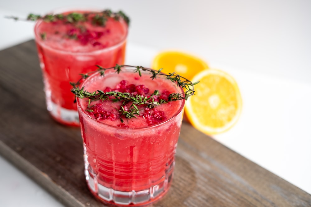 verre à boire transparent avec un liquide rouge et des tranches de citron