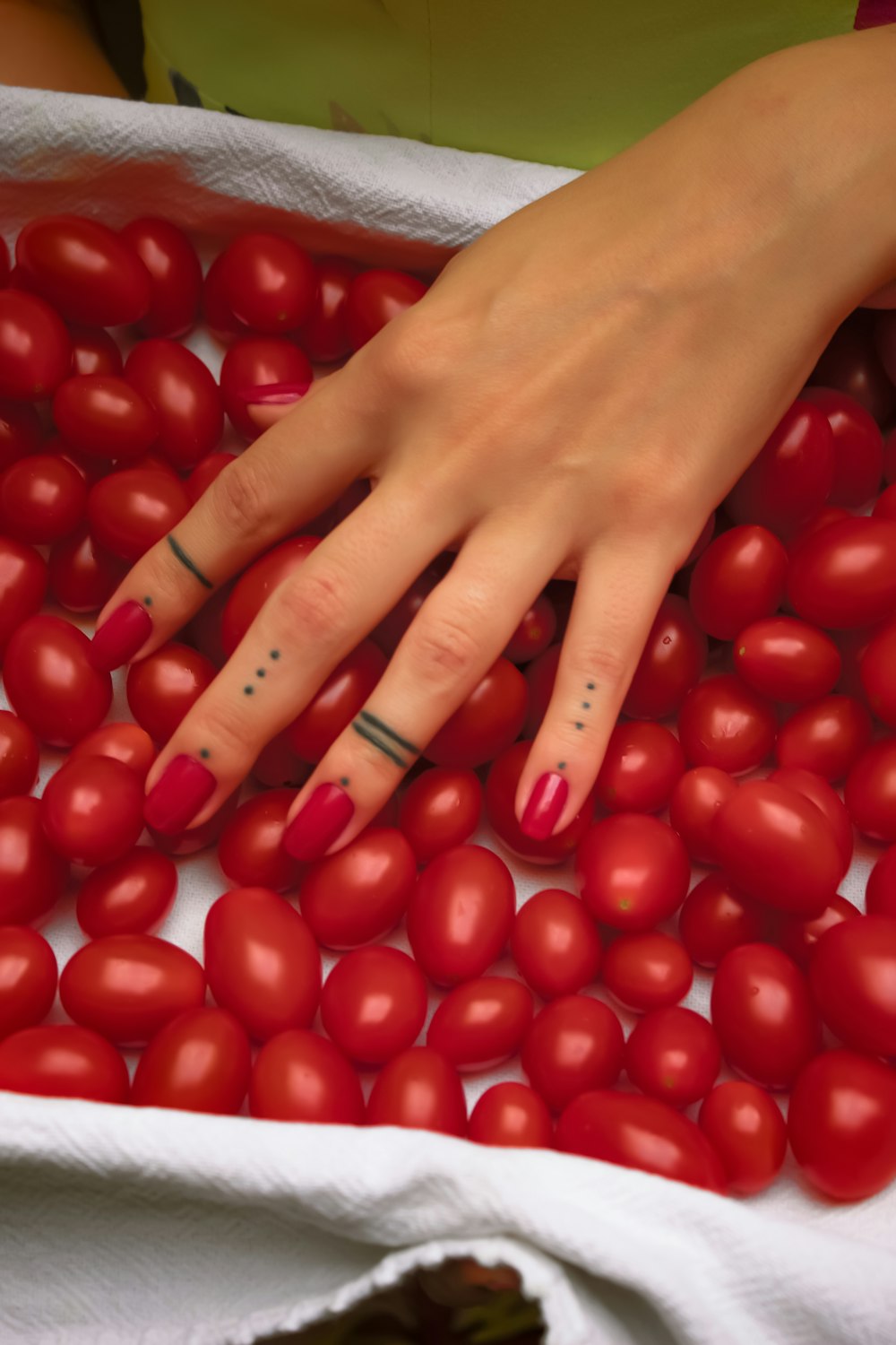 persona con manicura roja sosteniendo tomate rojo