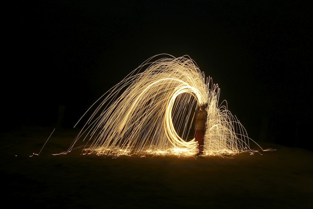 steel wool photography of person standing on road during night time