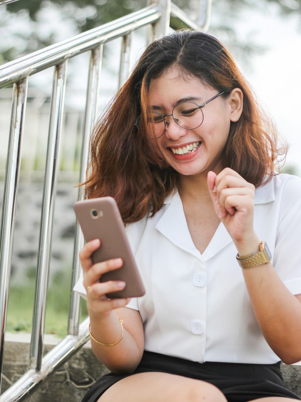 シルバーのiPhone 6を手にした白いボタンアップシャツの女性