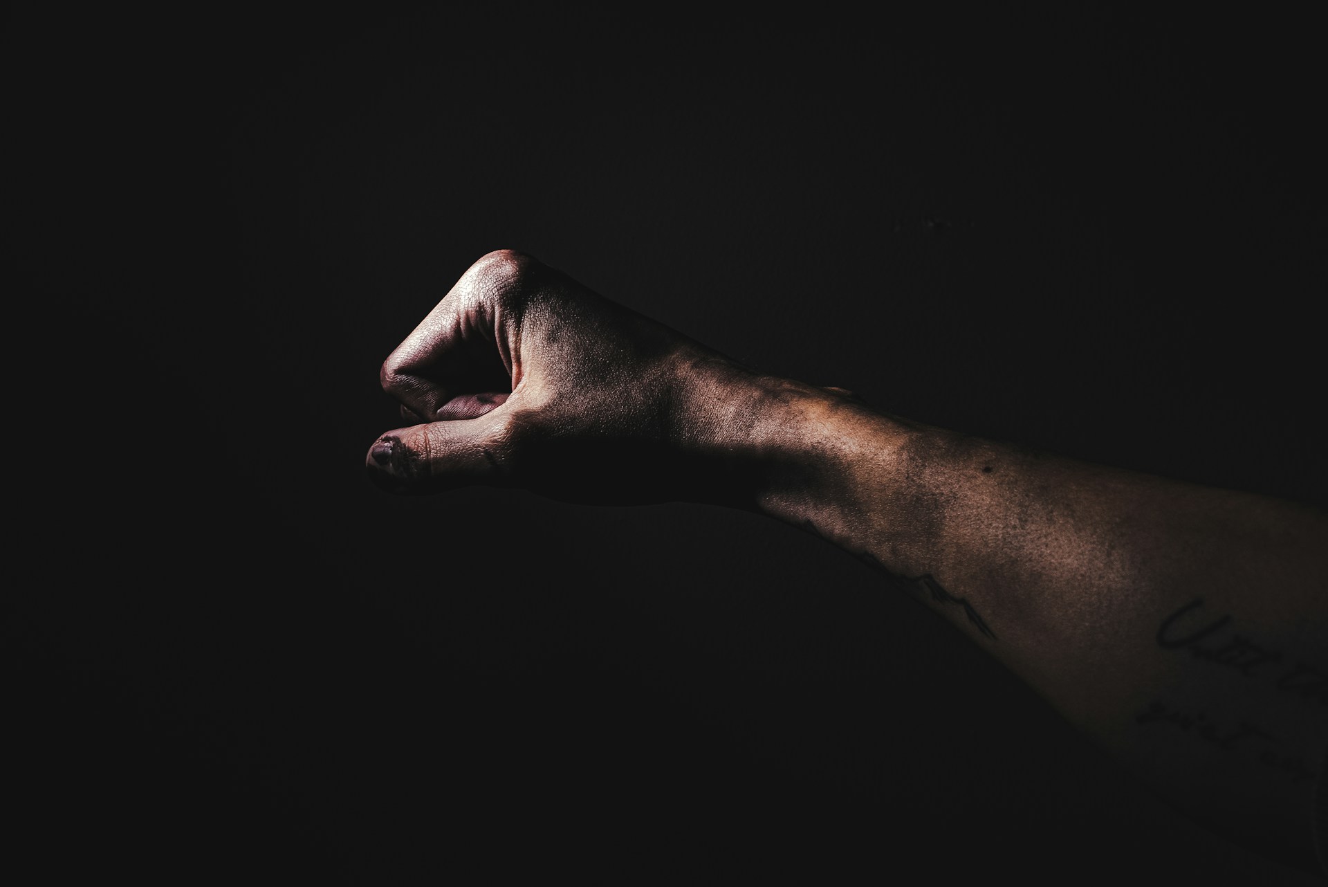 Close-up of a black and grey realistic tattoo portrait on forearm, showcasing fine details and shading.