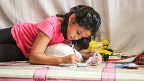 woman in red t-shirt writing on white paper