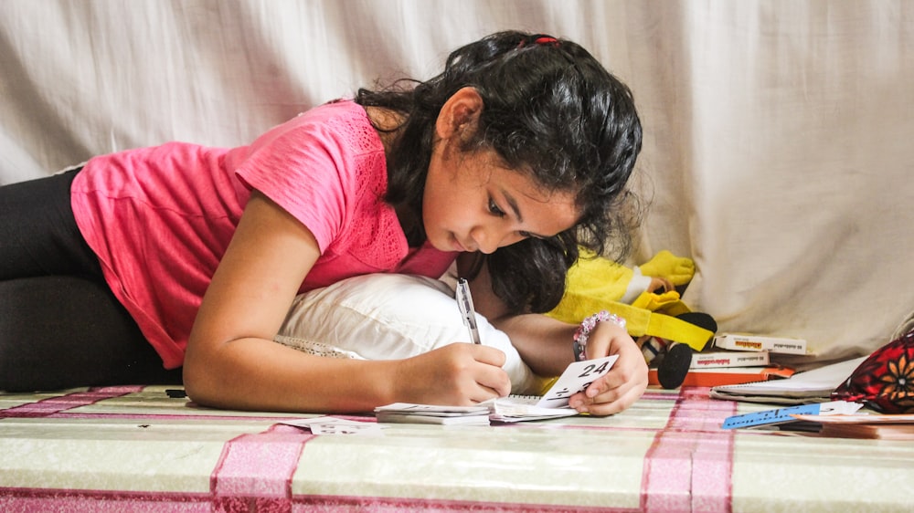 woman in red t-shirt writing on white paper