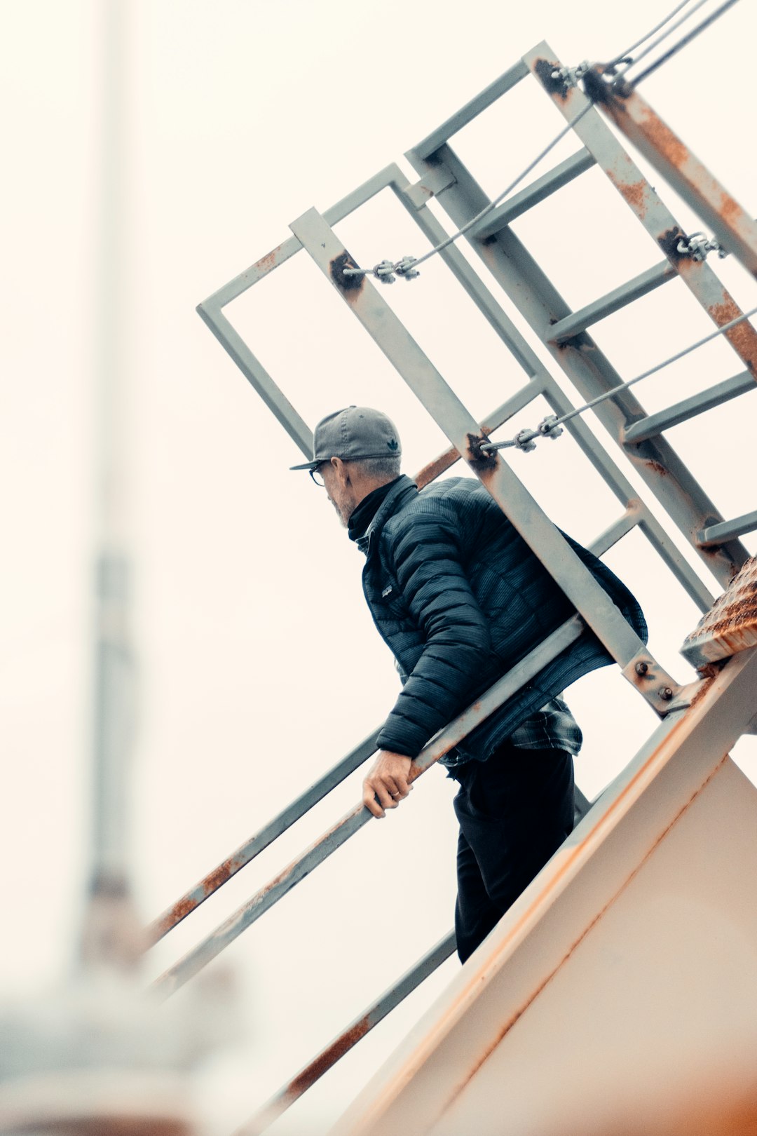 man in black jacket and blue denim jeans standing on brown wooden ladder during daytime