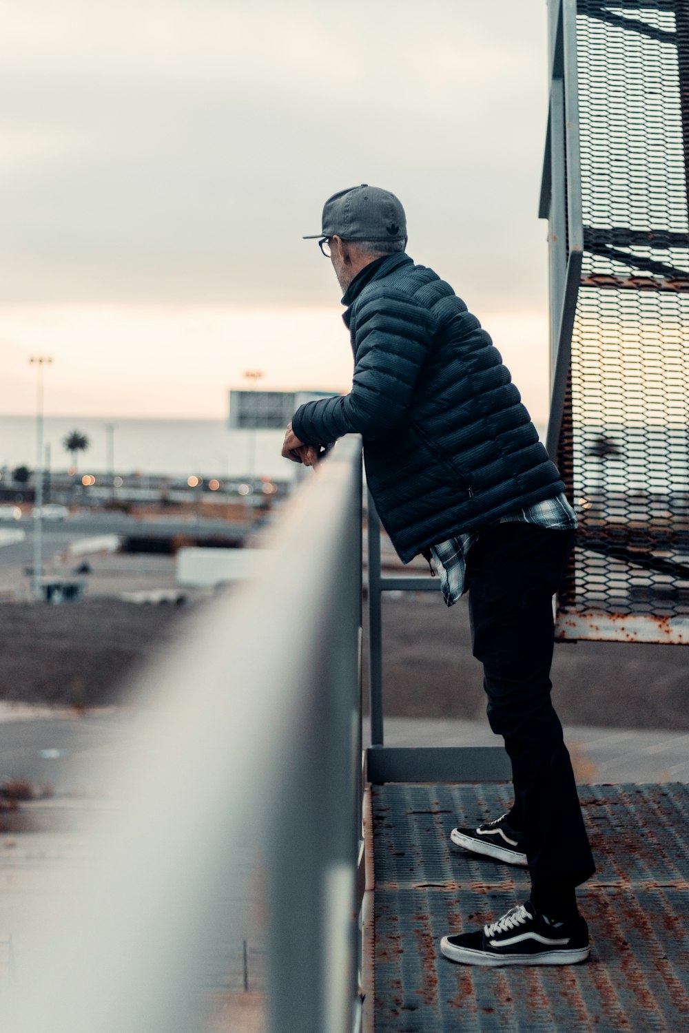 man in black and gray striped hoodie and black pants standing on bridge during daytime