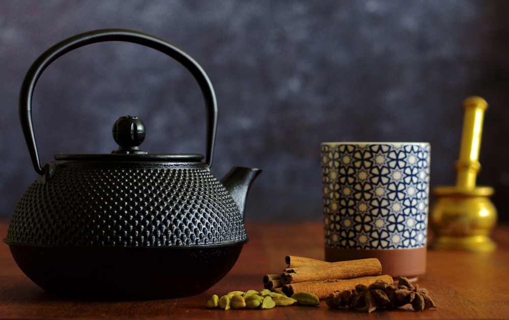 weiße und schwarze Keramik-Teekanne auf braunem Holztisch