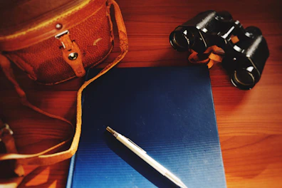 An elegant office bag placed on a polished wooden surface with a pen and planner.
