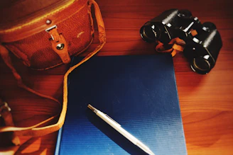 An elegant office bag placed on a polished wooden surface with a pen and planner.
