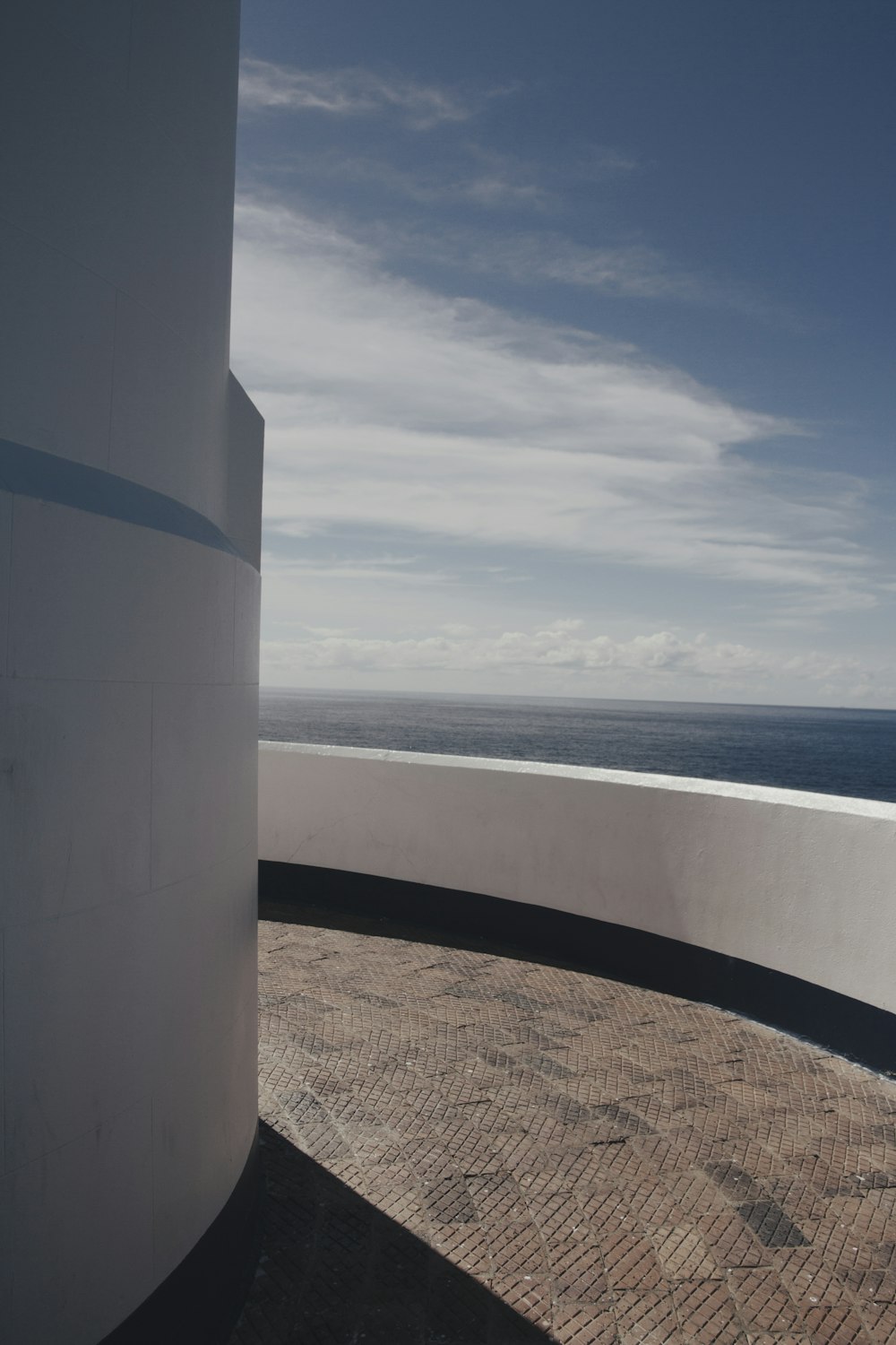 white concrete post near sea under white clouds during daytime