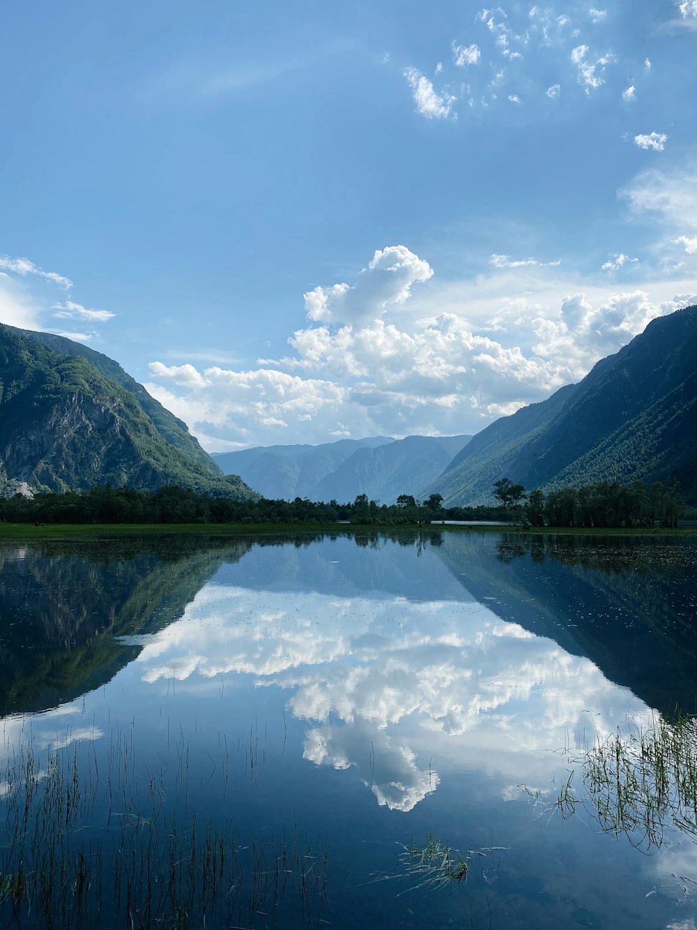 Montagne verdi accanto al lago sotto il cielo blu durante il giorno