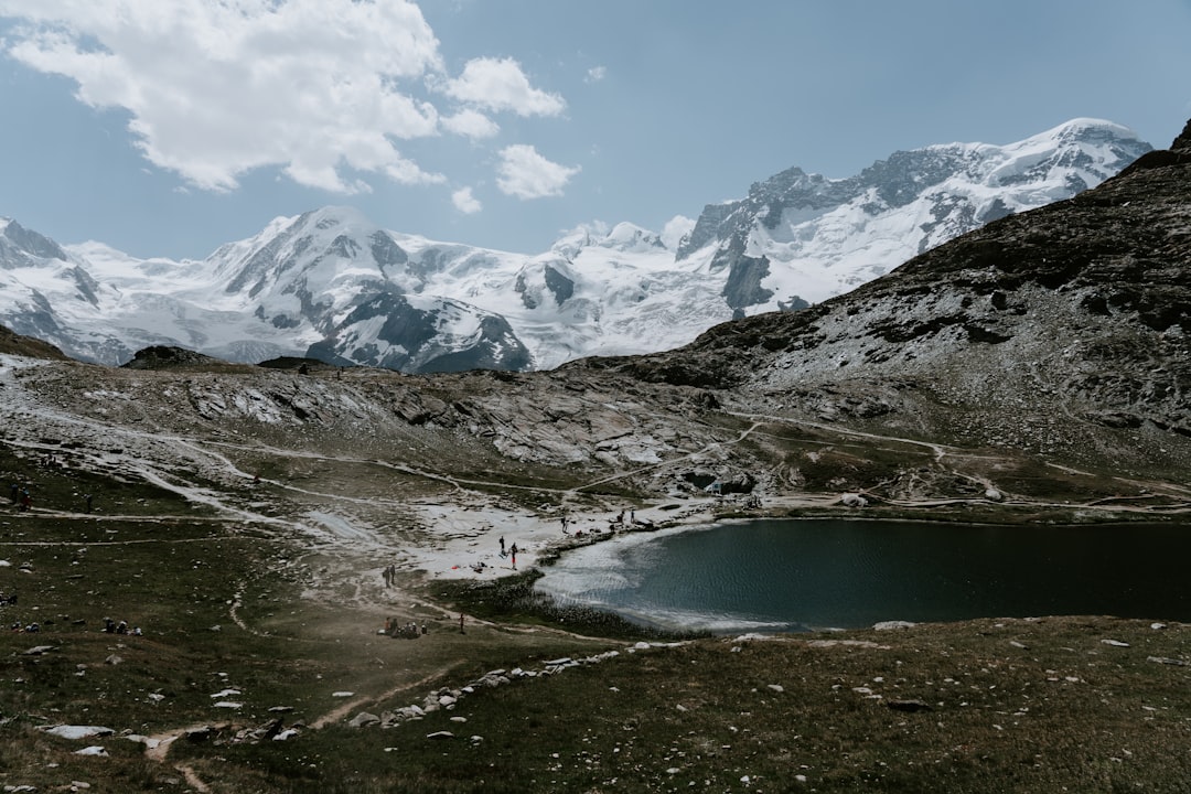 lake in the middle of mountains under white clouds and blue sky during daytime