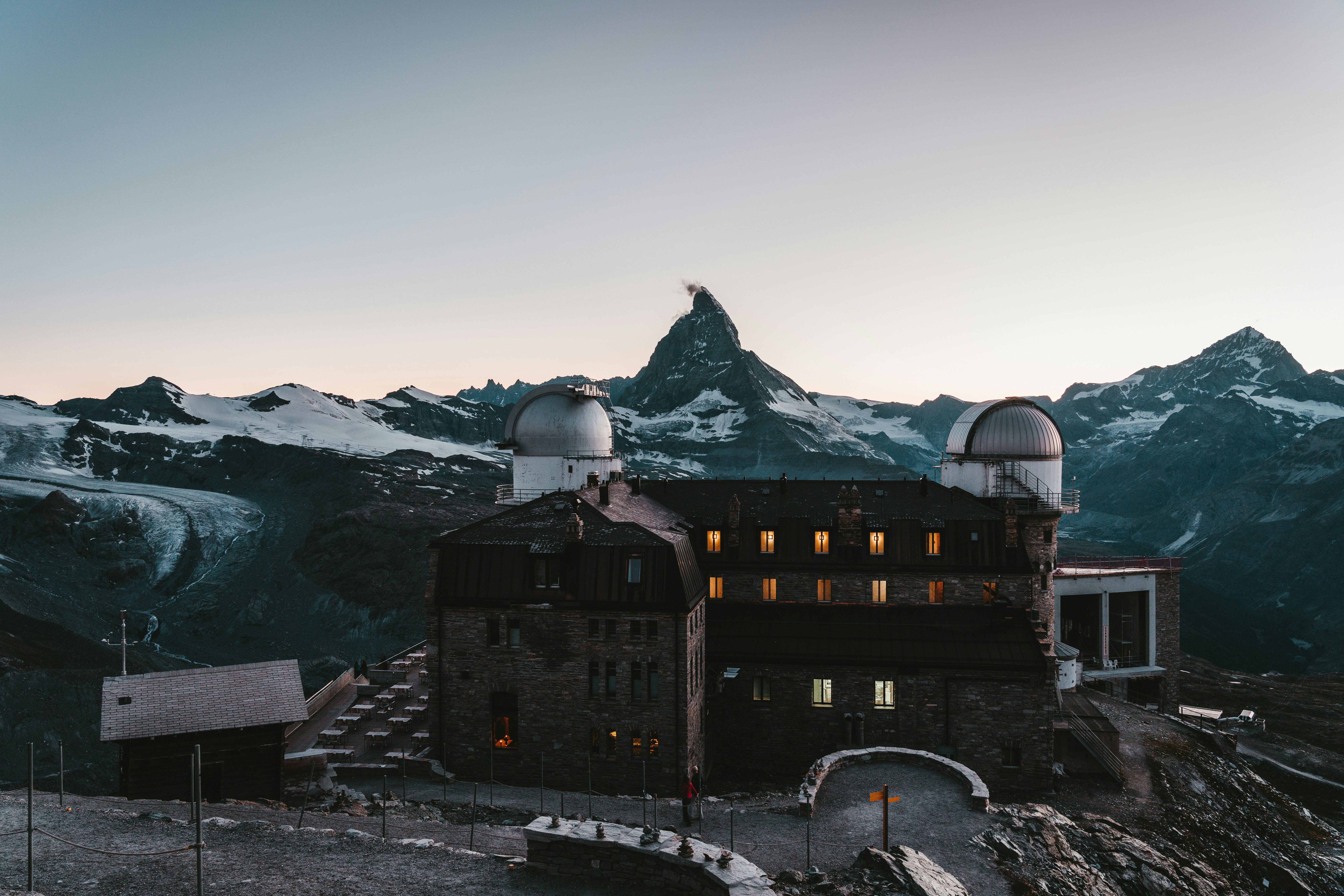 Schwarzes und braunes Betongebäude in der Nähe eines schneebedeckten Berges tagsüber