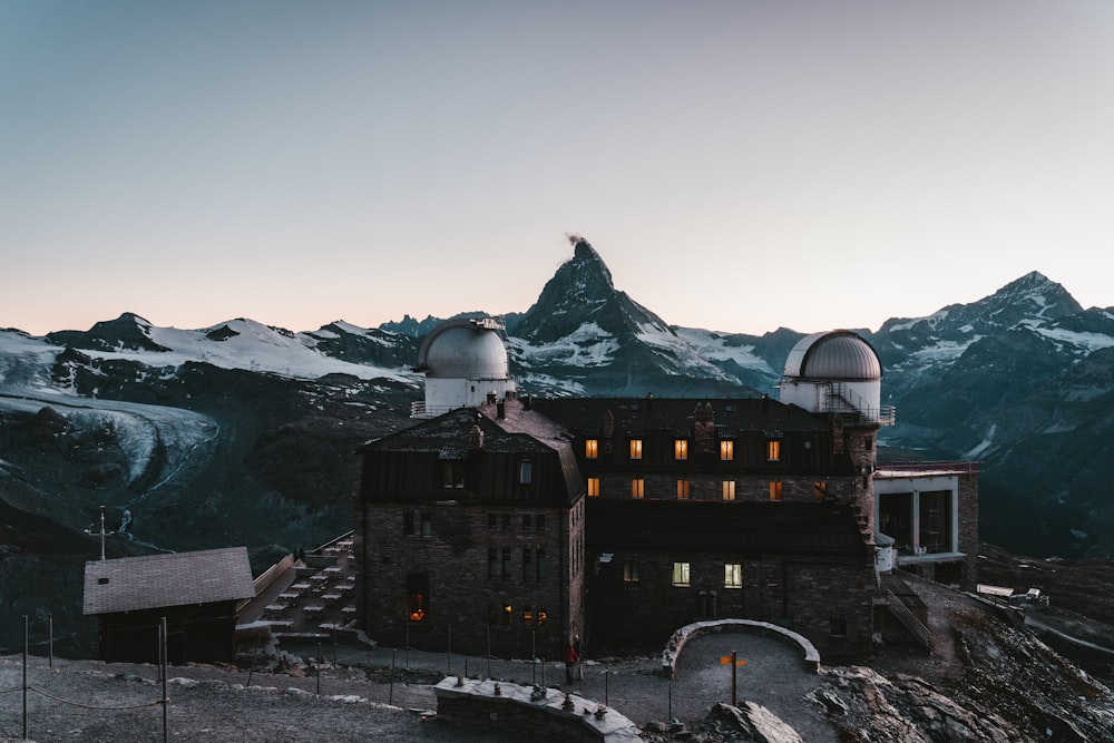 black and brown concrete building near snow covered mountain during daytime