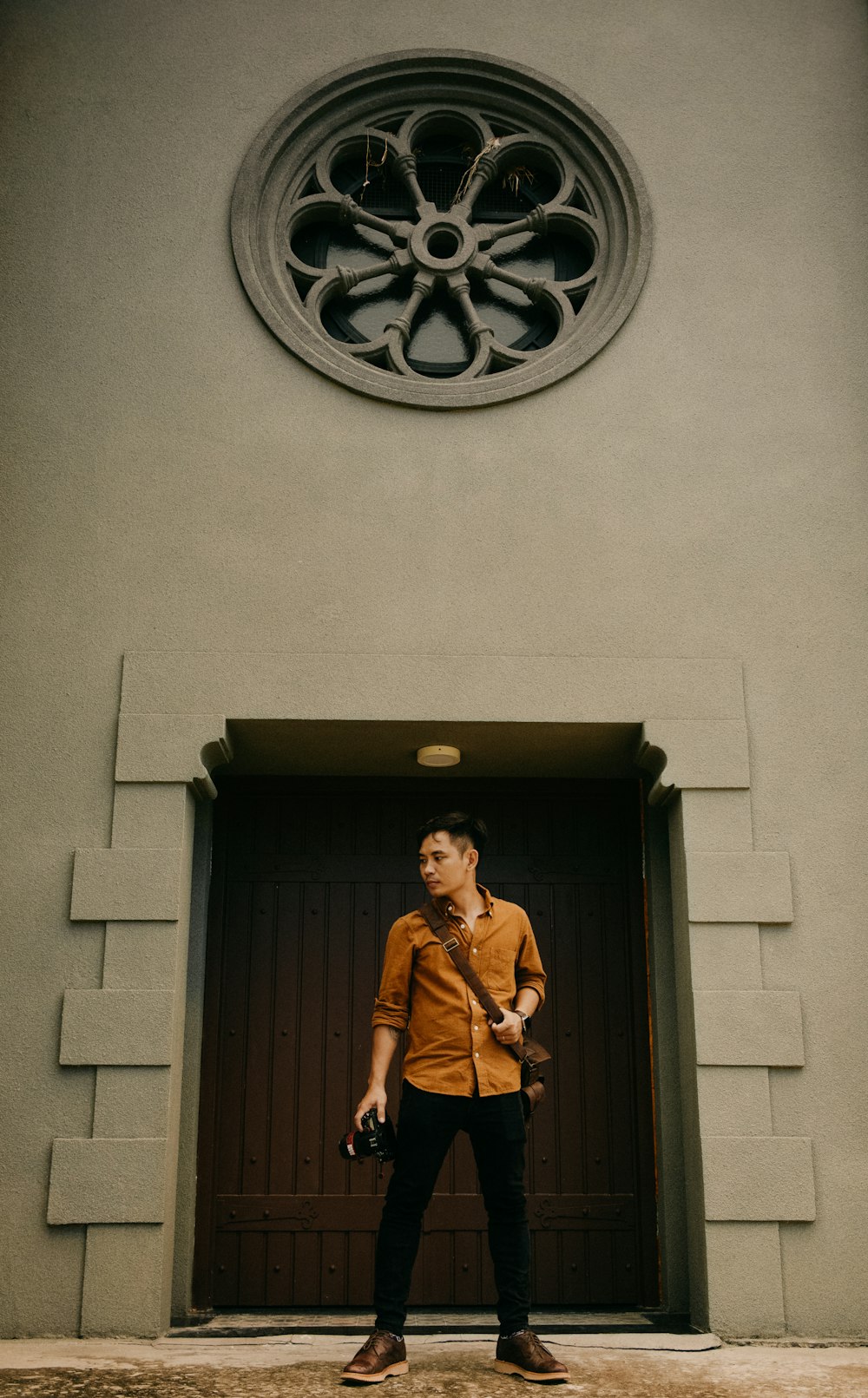 man in brown long sleeve shirt standing beside door