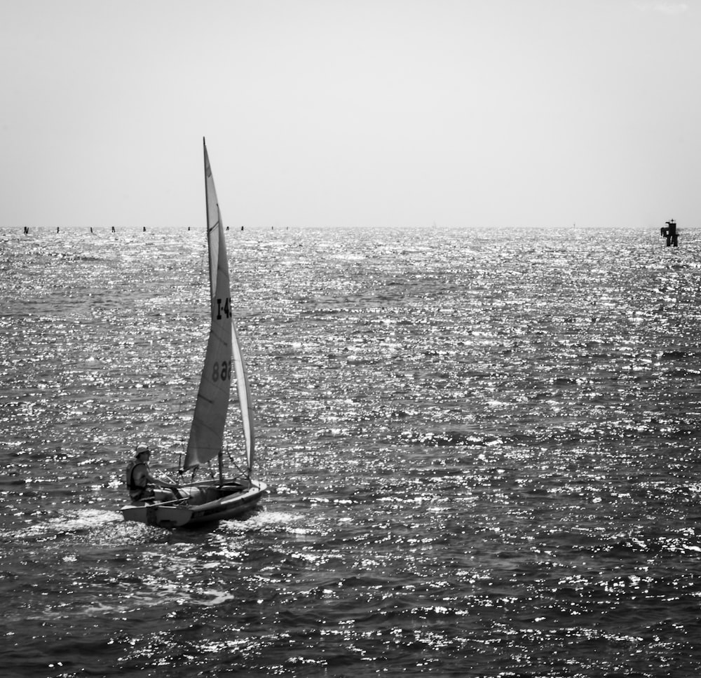 foto in scala di grigi della barca a vela in mare