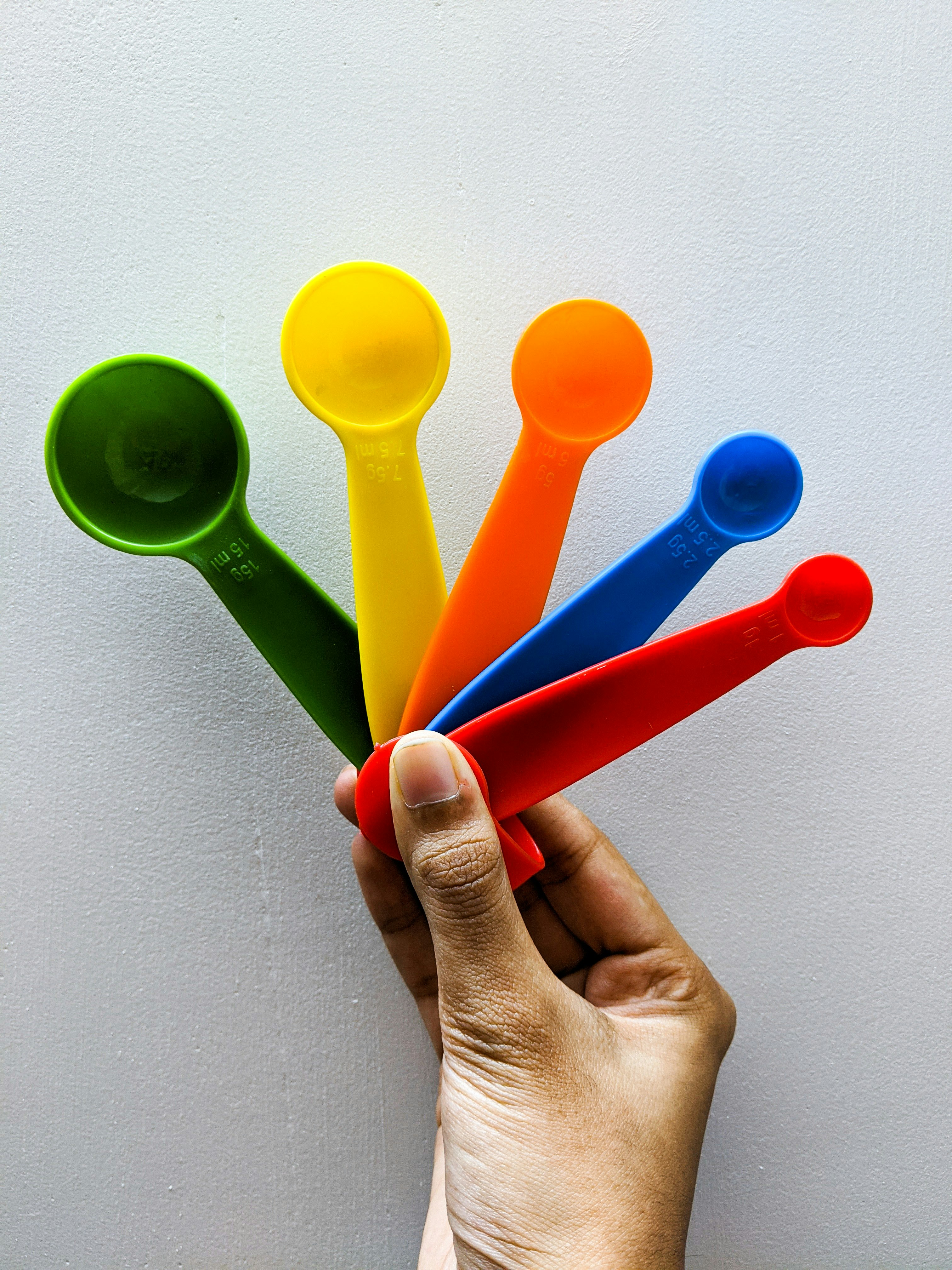 person holding green and red plastic spoons