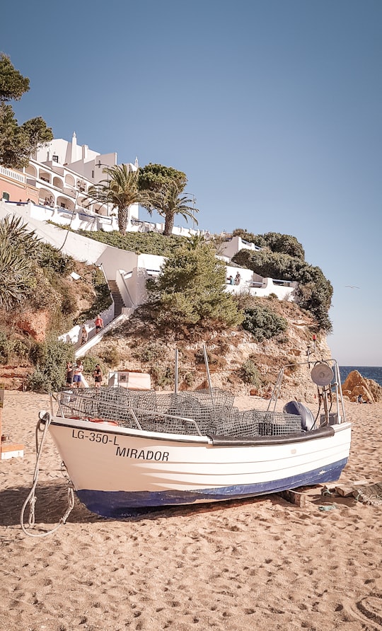 white and blue boat on beach during daytime in Carvoeiro Portugal