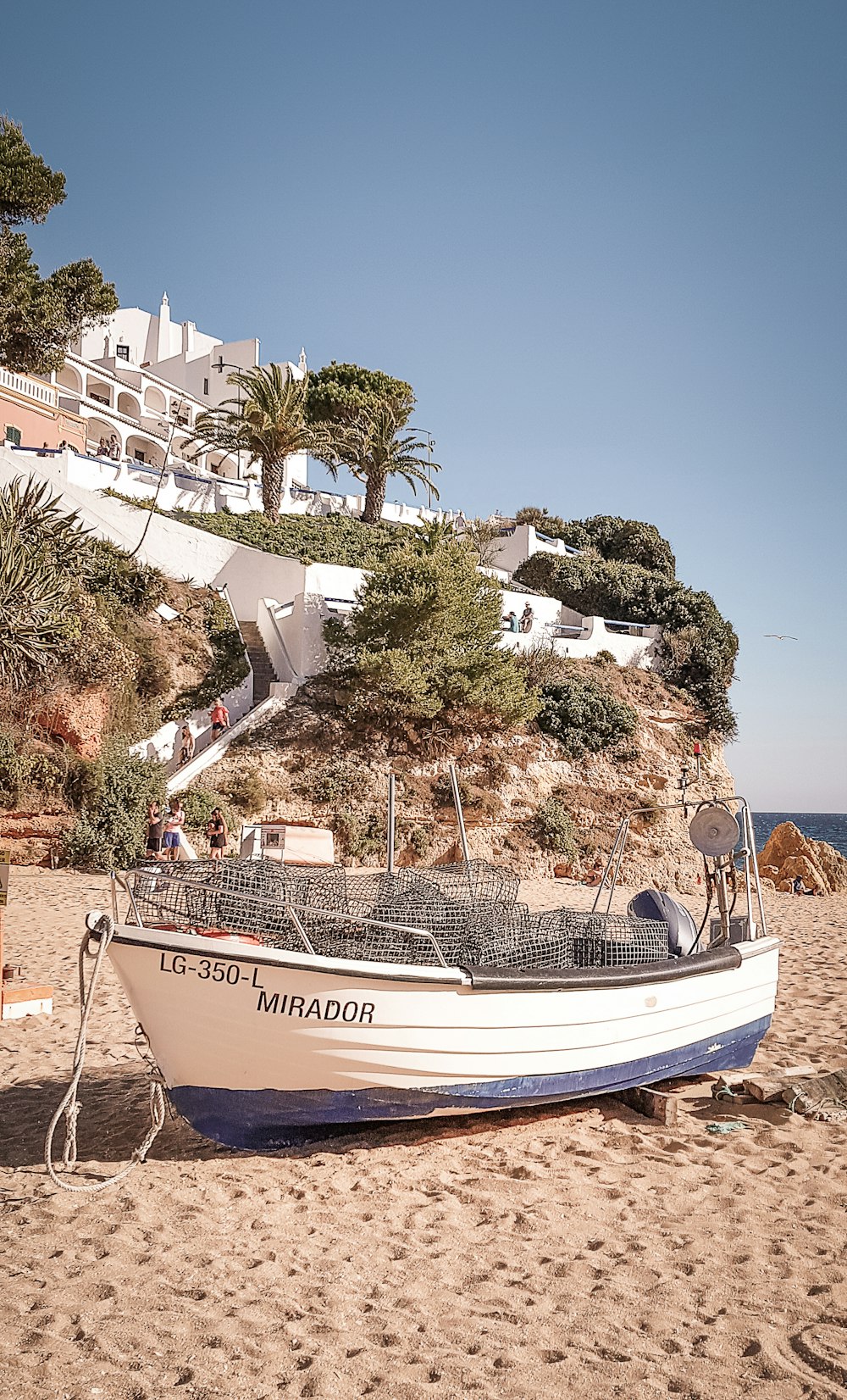 white and blue boat on beach during daytime