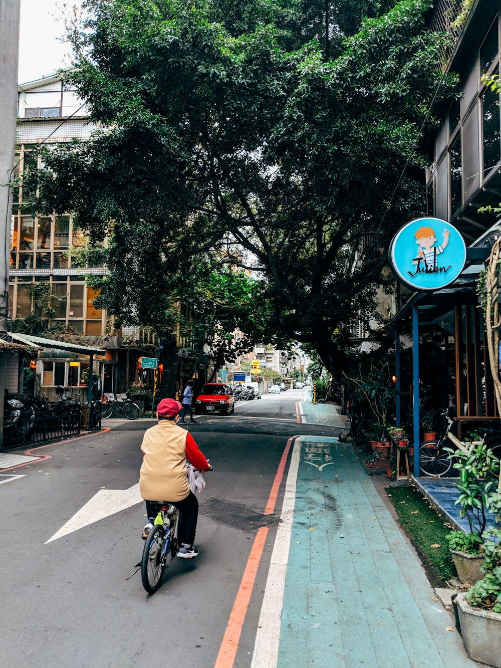 man in orange jacket riding bicycle on road during daytime