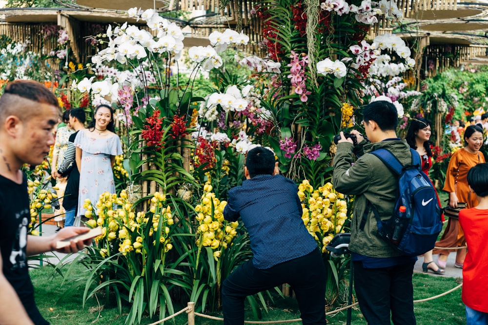 man in black jacket standing beside yellow flower