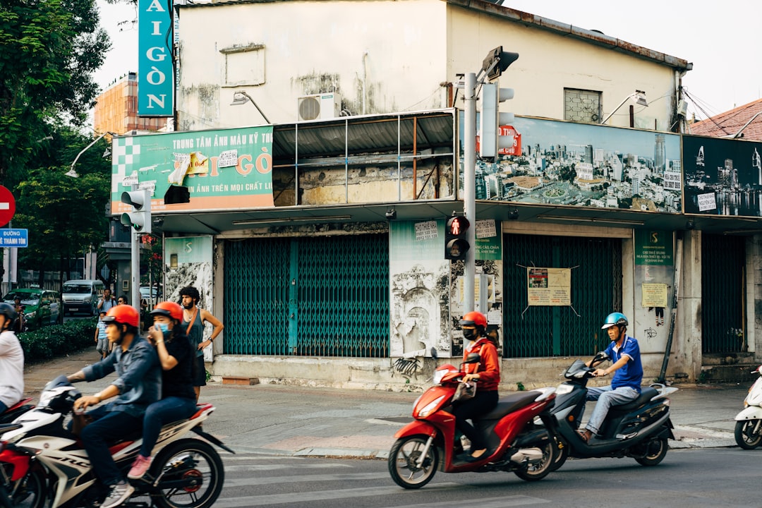 man in black t-shirt and blue denim jeans riding red motor scooter