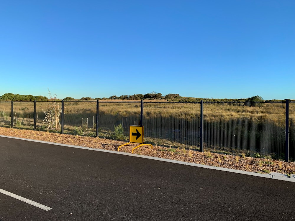 gray concrete road near green grass field under blue sky during daytime