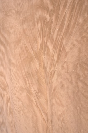 Fine sand with flowing patterns created by wind or water, displaying smooth, elegant textures and subtle wave-like designs across the surface.
