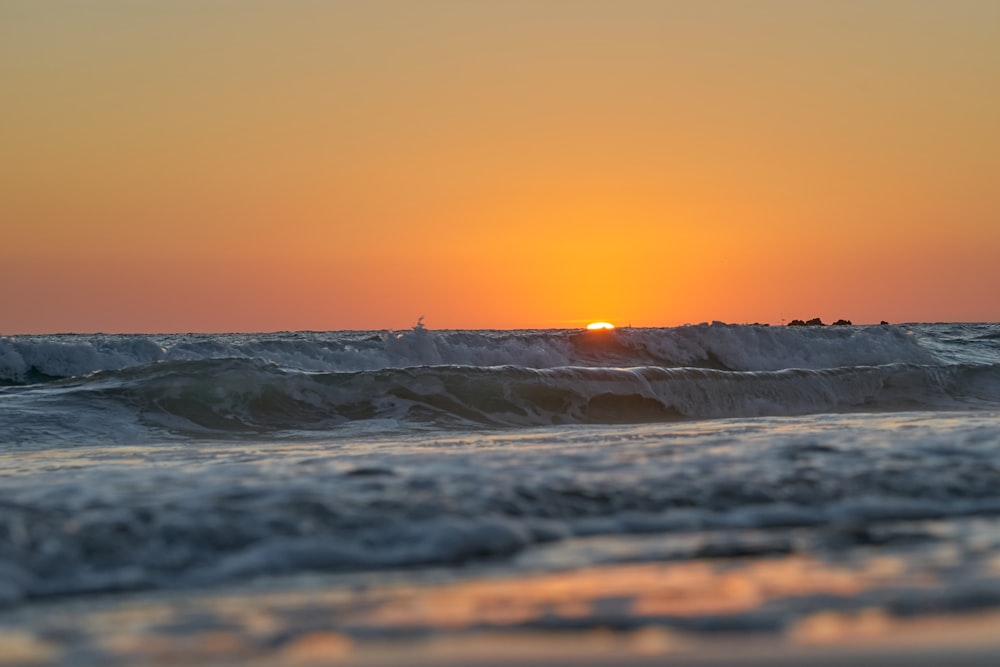 ocean waves crashing on shore during sunset