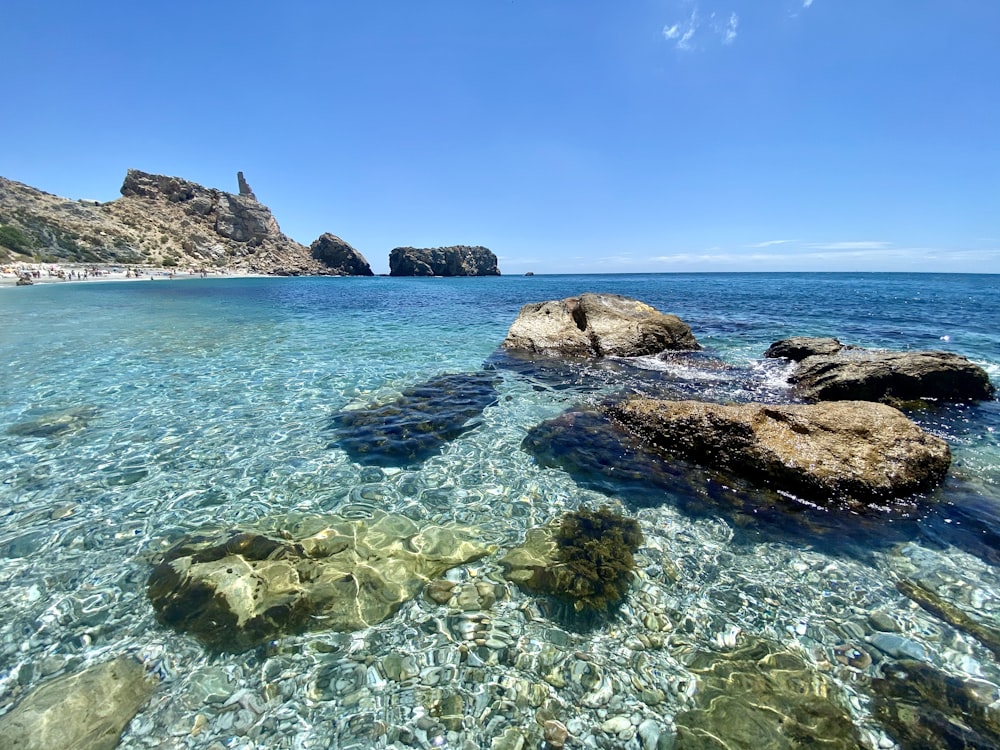 brown rock formation on sea under blue sky during daytime