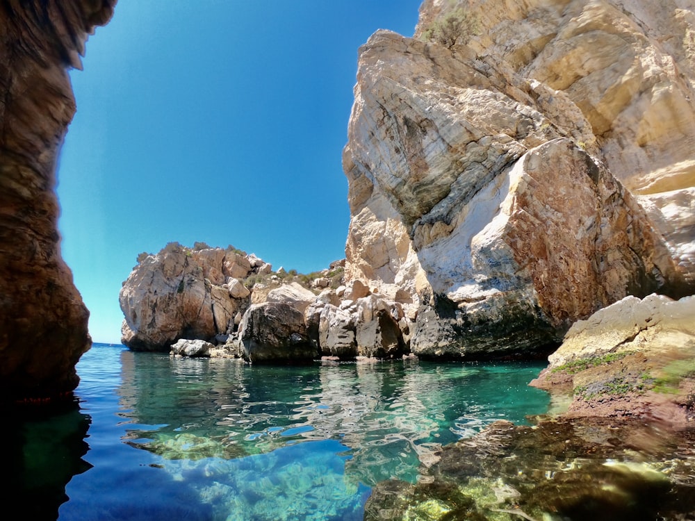 brown rock formation beside blue body of water during daytime