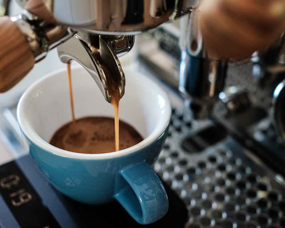 caneca de cerâmica azul na máquina de café expresso prateada