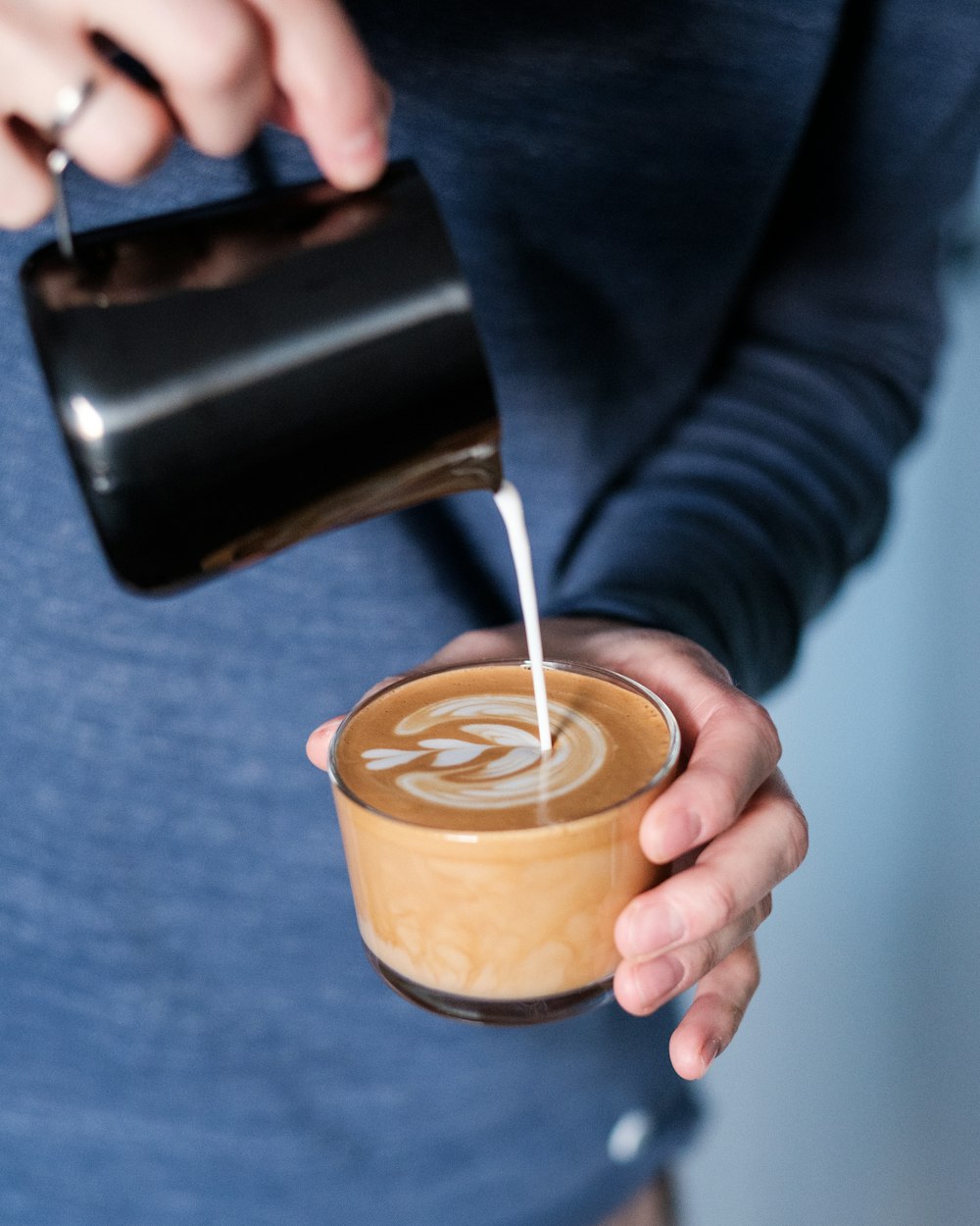 person pouring brown liquid on black ceramic mug