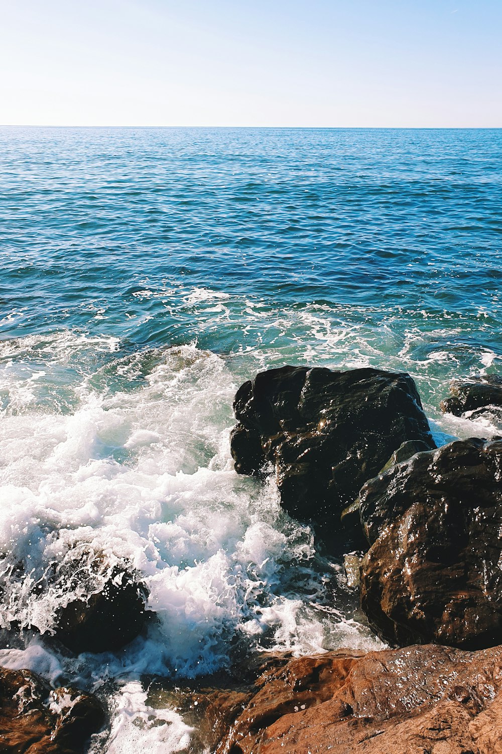 ocean waves crashing on rocky shore during daytime