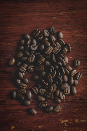 Aromatic dark roasted coffee beans in a wooden bowl on rustic table.