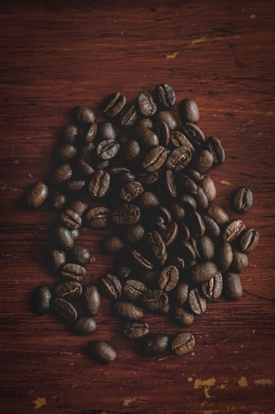 Close-up of freshly roasted coffee beans and cocoa pods on a rustic wooden table.